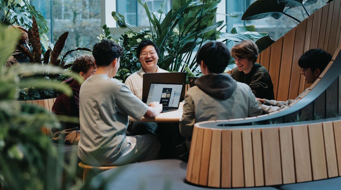 teens sitting around working on a tech problem in a group 