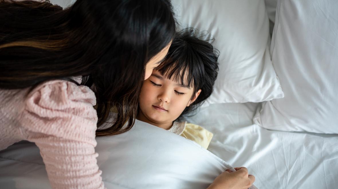mom tucking in daughter at night