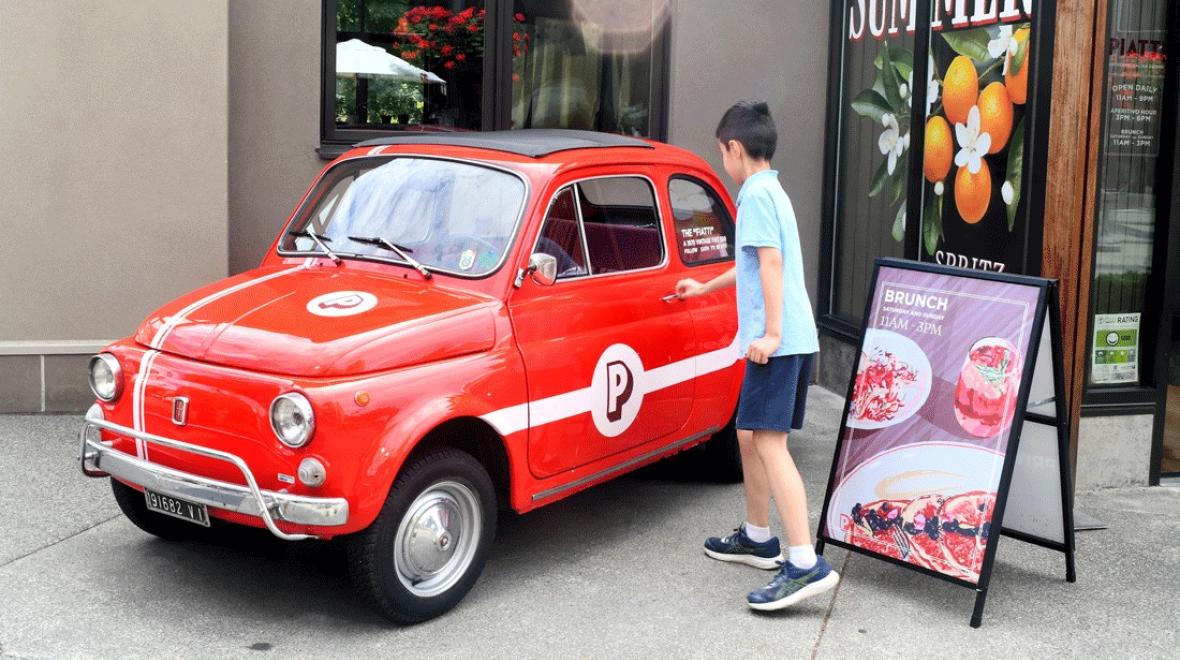 young boy walking up to vintage Fiat outside Piatti, a fun Seattle brunch spot