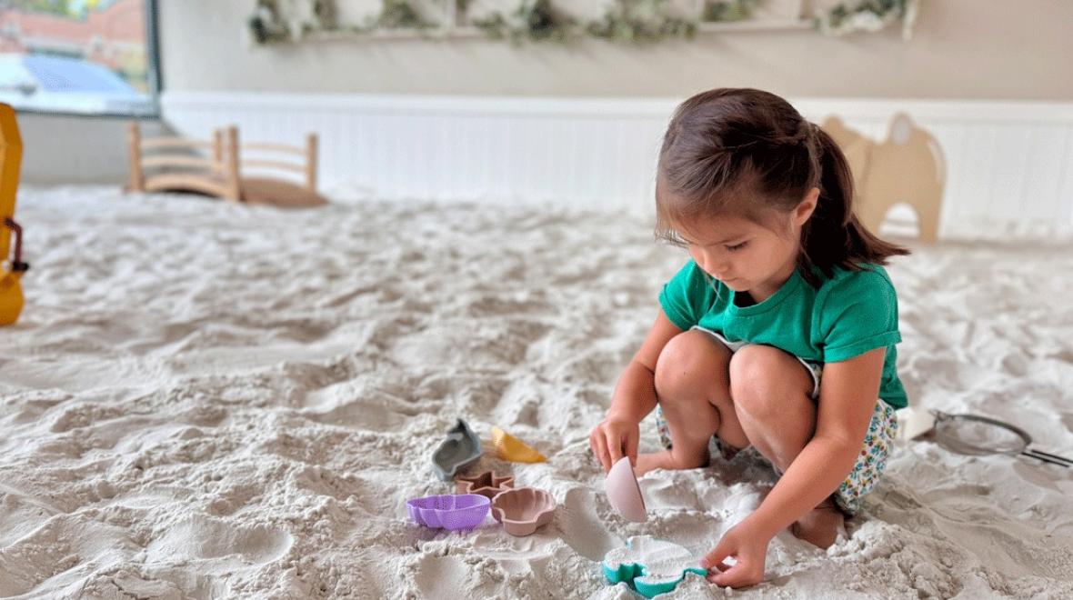 young girl scooping sand at an indoor sandbox in Issaquah
