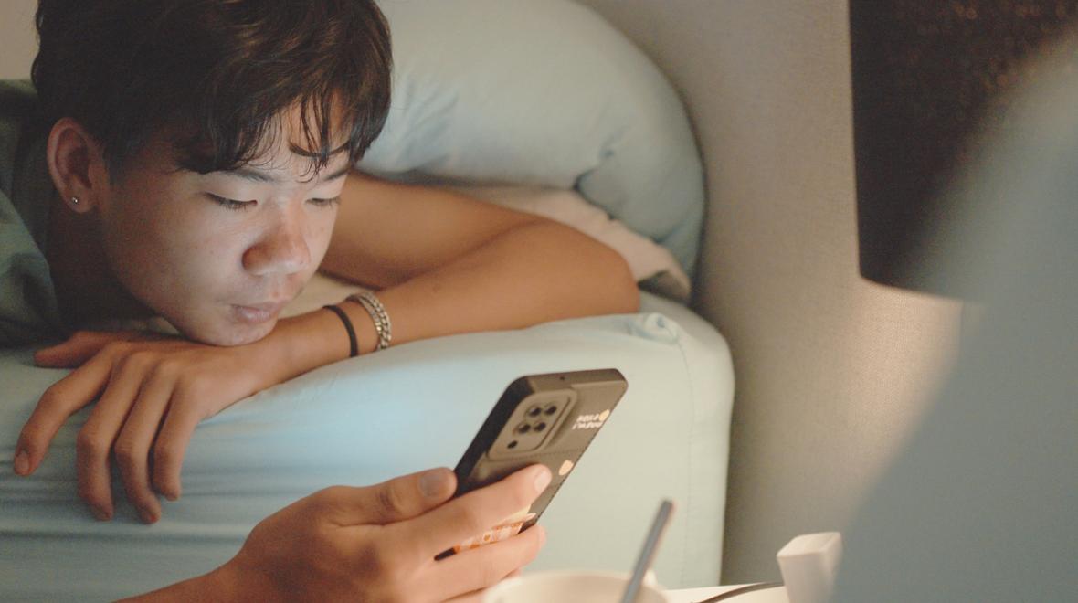 teen on bed looking at his phone