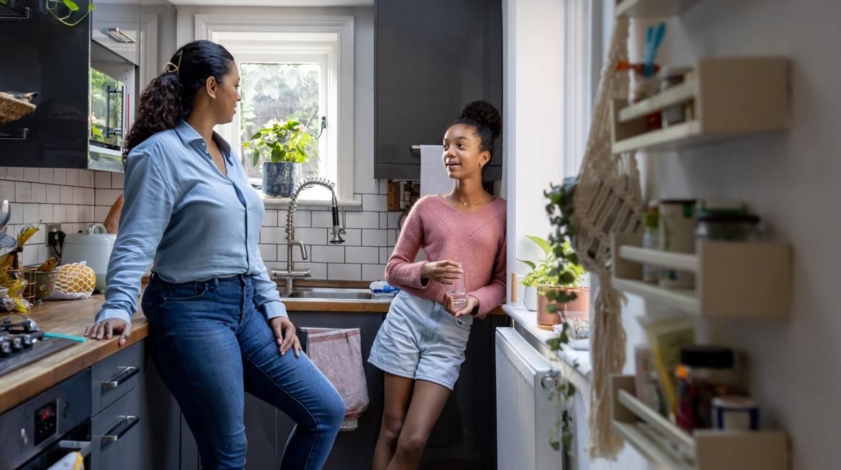 mom and teen daughter talking in the kitchen