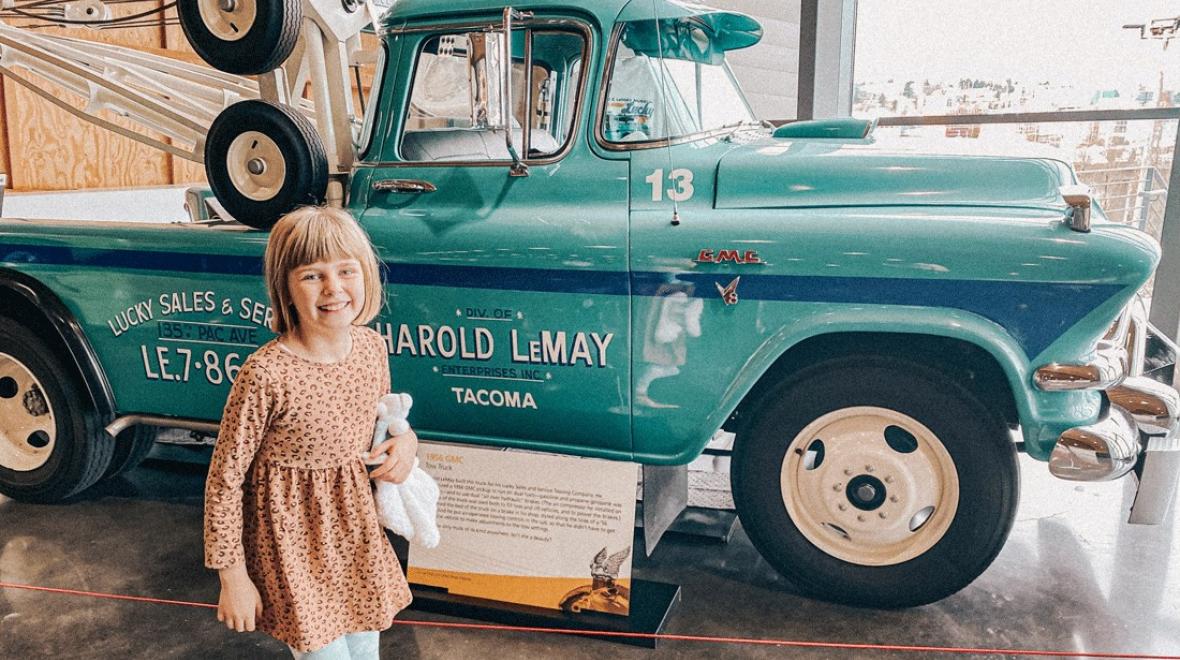preteen in front of a truck at LeMay – America's Car Museum in Tacoma, a fun place to take kids