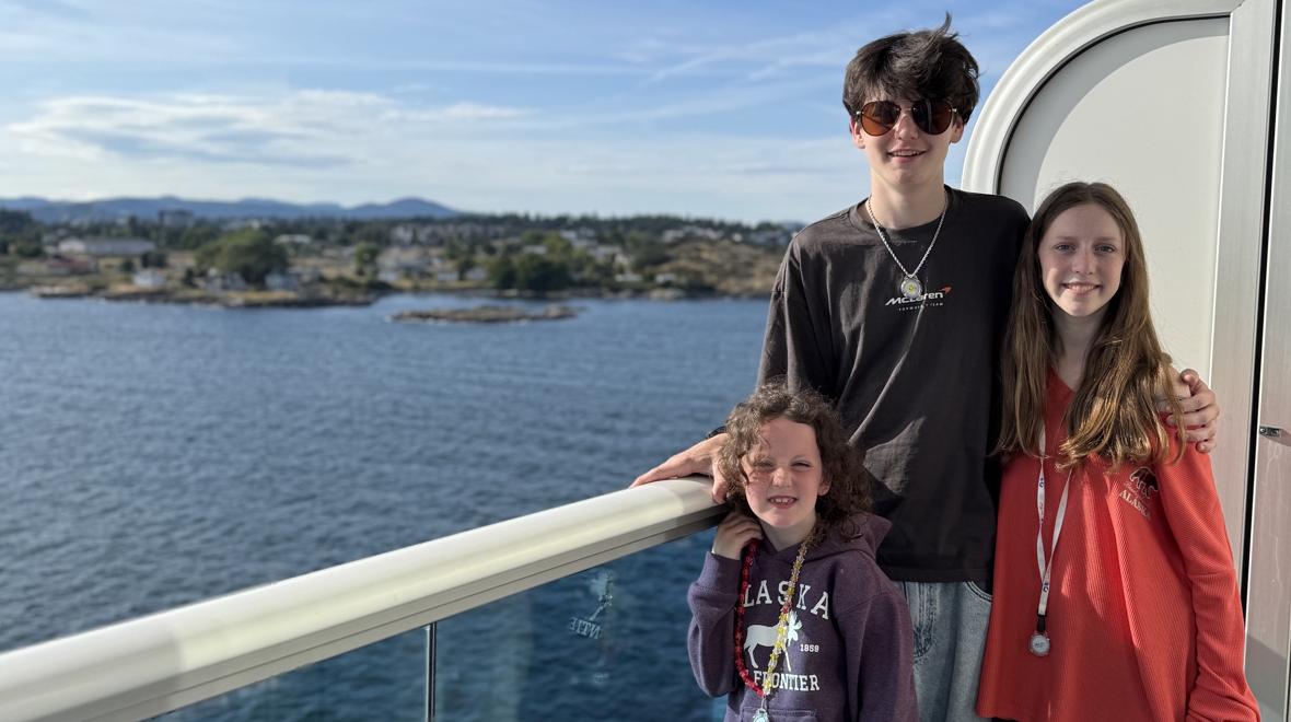 three kids standing on the deck of a cruise ship heading to Alaska
