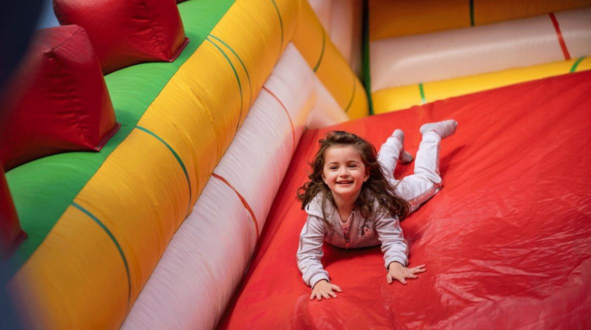 young girl sliding down inflatable slide during a seattle kids night out