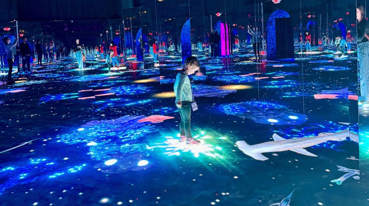 young girl stepping on illuminated sea floor at Bubble Planet