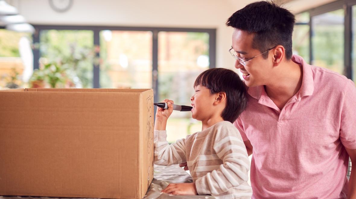 dad and son working on making a cardboard car track and train tunnel