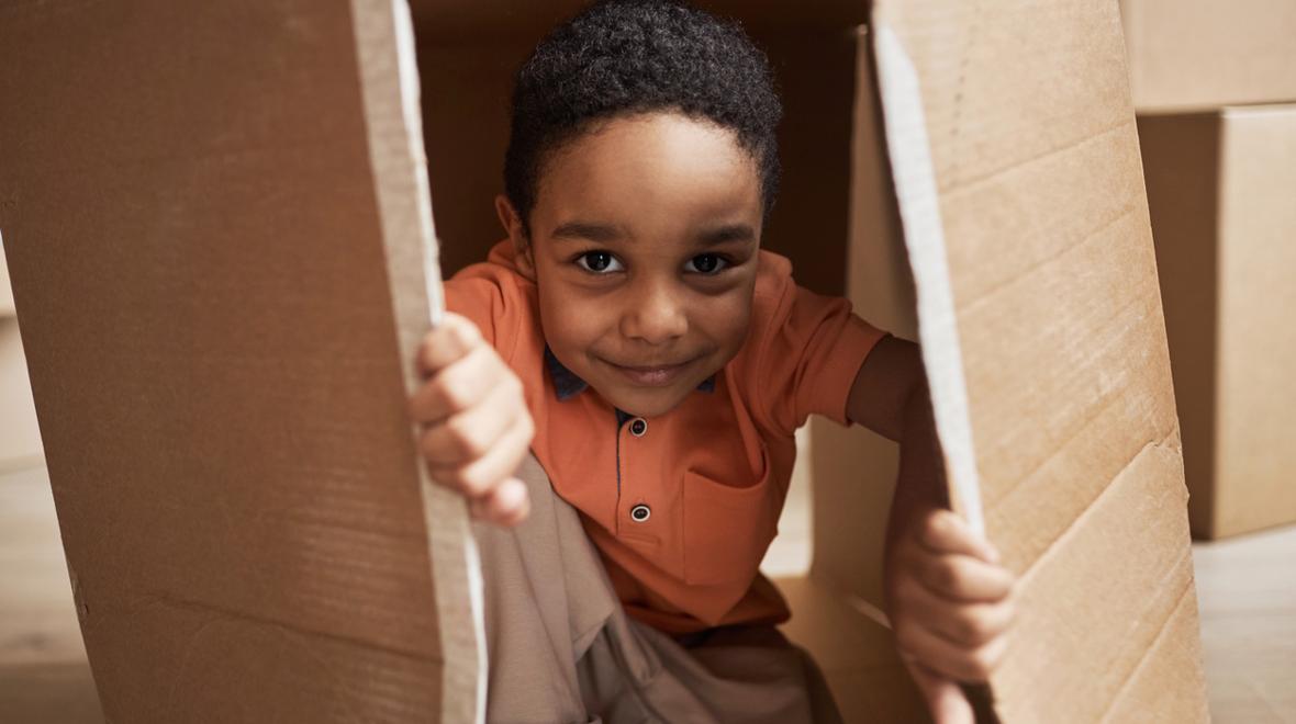 little boy playing in a cardboard box