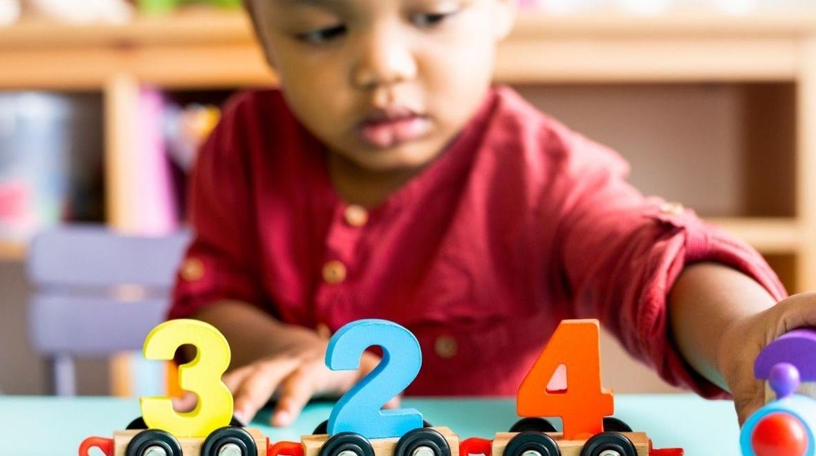 Little boy playing with mathematics wooden toy at child care