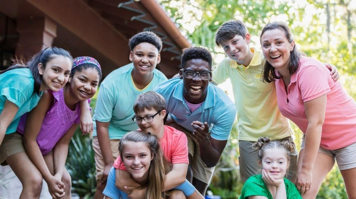 Group of teens and camp staff smiling together outdoors at camp