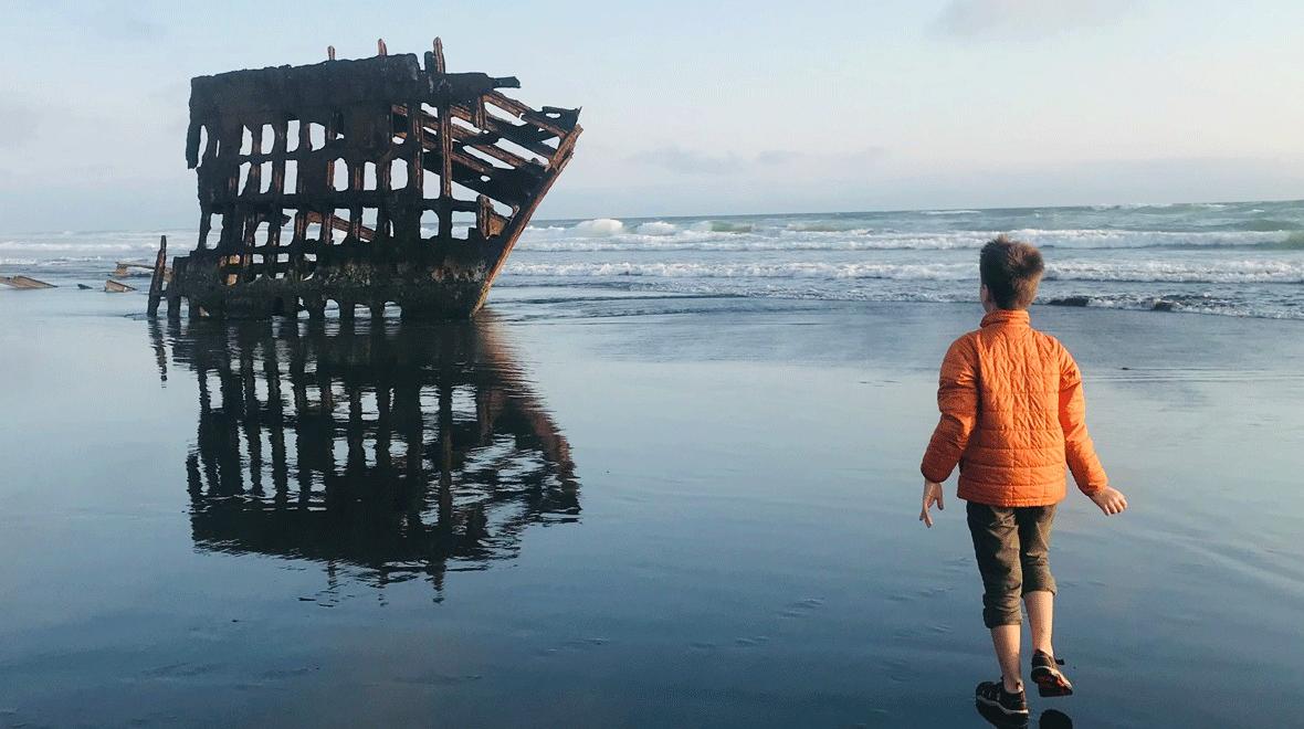 boy looking at the peter iredale shipwreck while camping in Oregon