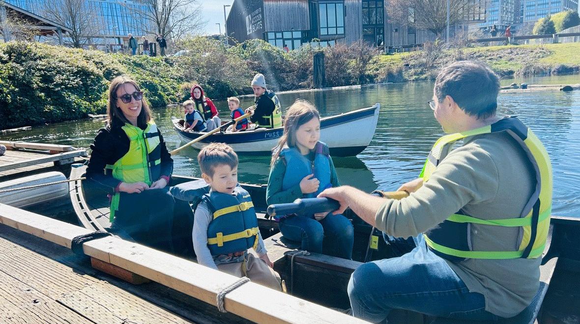 family of four rowing in a rowboat on South Lake Union in Seattle at The Center for Wooden Boats