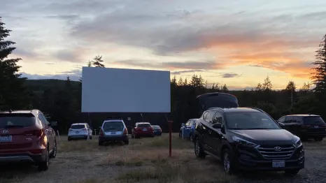 view of cars parked at a drive-in movie theater near Seattle at sunset