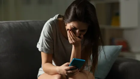 Upset teen girl receiving bad news online on her cell phone