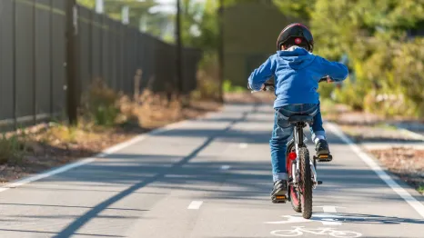Boy learning to ride a bike on a bike path