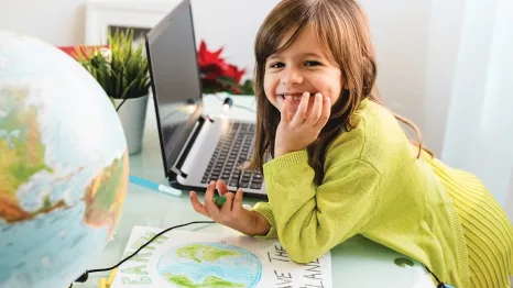Young girl with a globe and computer making a Save The Earth sign