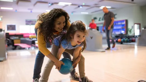 Mother and daughter smiling while bowling at a Seattle bowling alley
