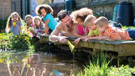A group of kids on a small bridge over a pound at a seattle outdoor summer camp