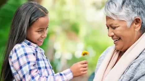 Young girl giving older woman a flower and spreading kindness
