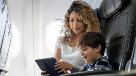 mom and son looking at a tablet on an airplane