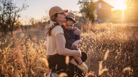 mom holding her son in a wheat field at sunset pregnancy loss