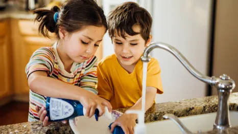 two responsible kids helping with chores by doing the dishes
