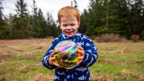 young child holding a glass float found during Northwest Glass Quest, a glass float hunt on Camano Island