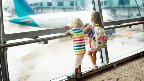 two kids looking out a window at an airplane SEA airport