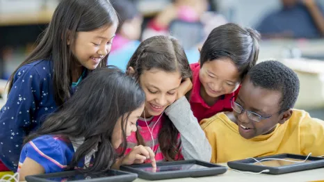 kids gathered around a tablet at school