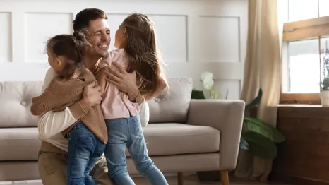 dad hugging two young daughters