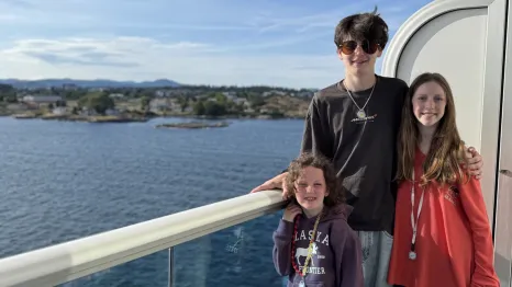 three kids standing on the deck of a cruise ship heading to Alaska