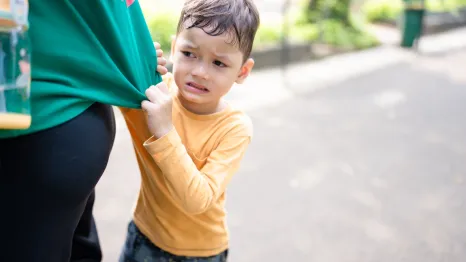 young boy tugging on his mother's shirt