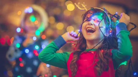 little girl laughing and playing with holiday lights