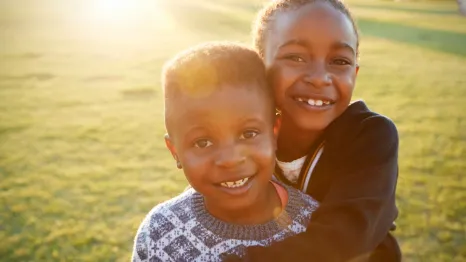 Black History Month events with smiling African American boy and girl hugging each other. 