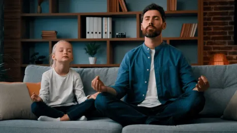 young father teaching little daughter meditation