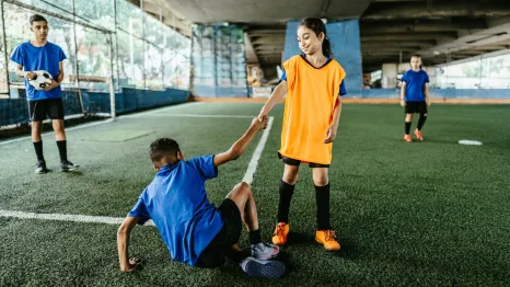 soccer player helping another player to their feet