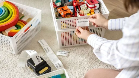 woman holding mobile label printer sticker with kids toys