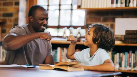 Teacher and student giving each other a high five in a library