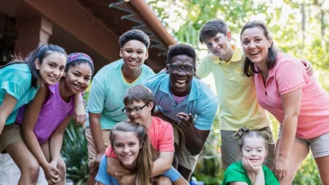 Group of teens and camp staff smiling together outdoors at camp