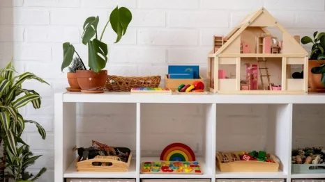 Montessori material white shelves in a room with neatly arranged toys