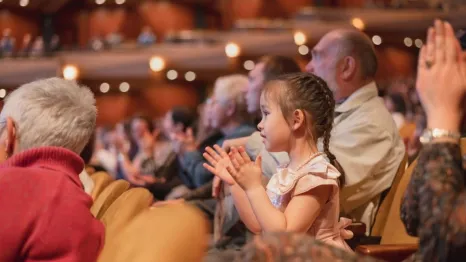 little girl clapping hands in a concert hall