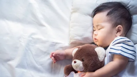Newborn baby sleeping with teddy bear