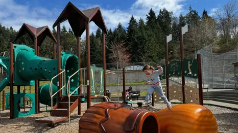 girl jumping across climbers at Shoreview Park's baseball playground