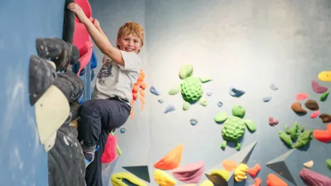 young boy climbing at an indoor rock climbing gym in Seattle