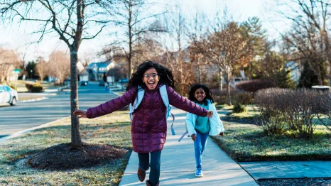 two girls running down the street happy to be out of school