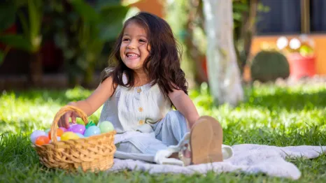 girl sitting with an Easter basket in the grass