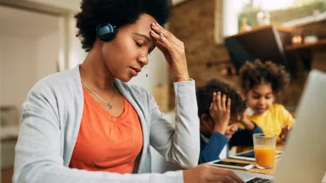 overcommitted mom looking stressed out with kids in the background