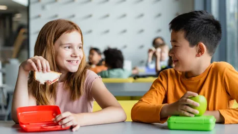 two kids eating lunch together at school