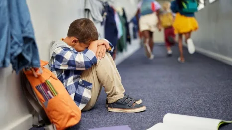 little boy sitting in corridor anxious at end of school 