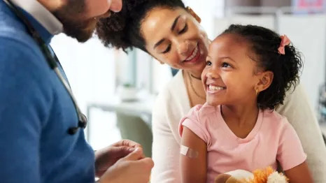 little girl at a primary health checkup with mother and doctor